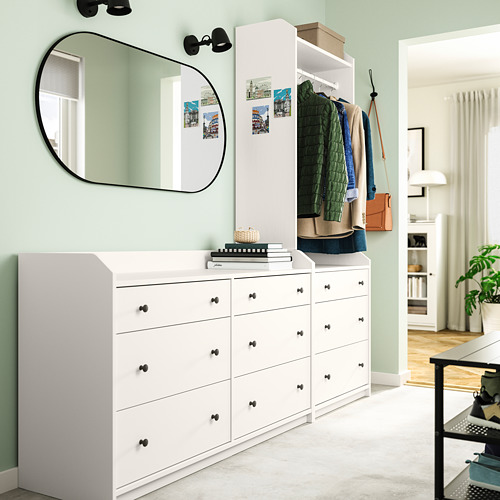 Moderna sala verde con tocadores y espejo HAUGA blancos, donde se exhibe ropa y accesorios.