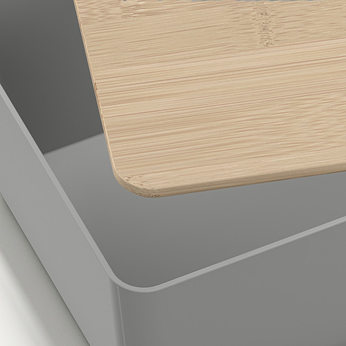 Un primer plano de una caja de almacenamiento bien elaborada con una tapa de bambú lisa y un elegante cuerpo de plástico gris, que muestra un diseño fino y calidad.