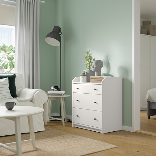 Pequeña cómoda blanca en una sala de estar moderna con paredes de color verde claro.