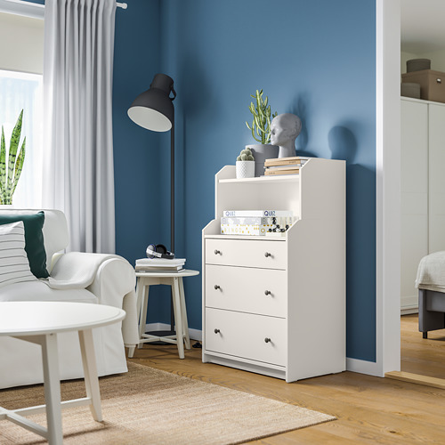 Sala de estar moderna con cofre HAUGA blanco, pared azul, plantas y sofá blanco.