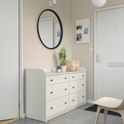 Moderna configuración de entrada con tocador HAUGA blanco, espejo redondo, tablero perforado y cactus.