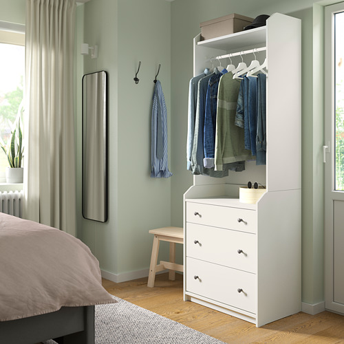 Dormitorio con tocador HAUGA blanco, ropa tendida, espejo, cama y piso de madera.