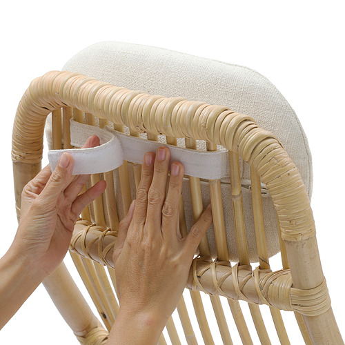 La persona está montando una silla de ratán tejido, insertando un cojín con espuma.