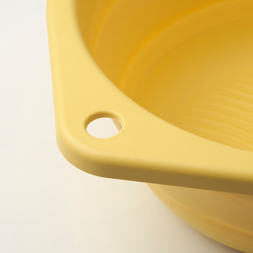 El lavabo de plástico amarillo brillante se colapsó en un disco plano, mostrando un diseño robusto y que ahorra espacio.