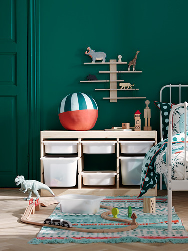 Sala de juegos para niños con paredes verdes, muebles blancos, juguetes de madera, alfombra colorida y una figura de dinosaurio.