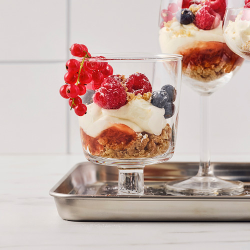 Tazón de postre de vidrio en bandeja, con frutas en capas y crema, que muestra versatilidad para servir dulces.