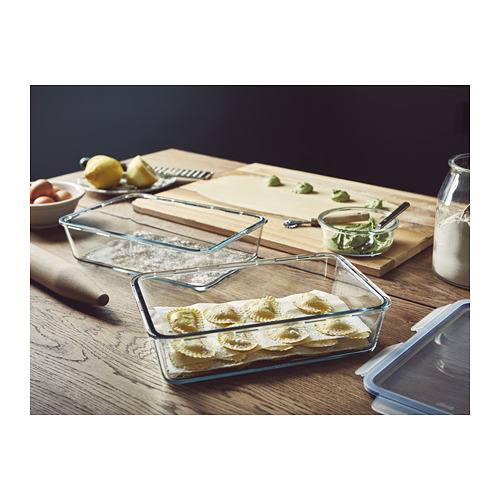 Recipiente de vidrio IKEA 365+ sobre mesa de madera, relleno de raviolis. Transparente con tapa a presión, ideal para uso en la cocina.