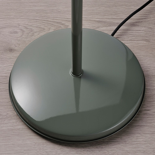 Moderna base de lámpara de pie verde con superficie reflectante sobre suelo de madera.