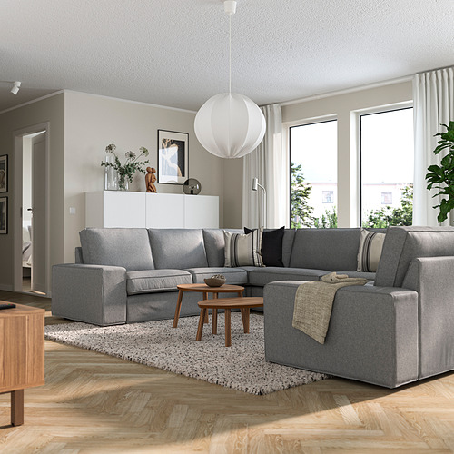 Sala de estar moderna con sofá KIVIK, modular, mesa de centro, lámpara colgante y ventanas, acentuadas con plantas.