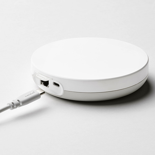 Un concentrador DIRIGERA blanco de ikea con puertos usb-c y micro-usb, que se conecta a un enrutador para el control inteligente del hogar.