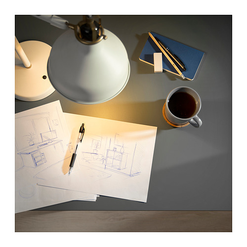 Configuración de escritorio de trabajo con lámpara, boceto, bolígrafo, cuaderno y café.