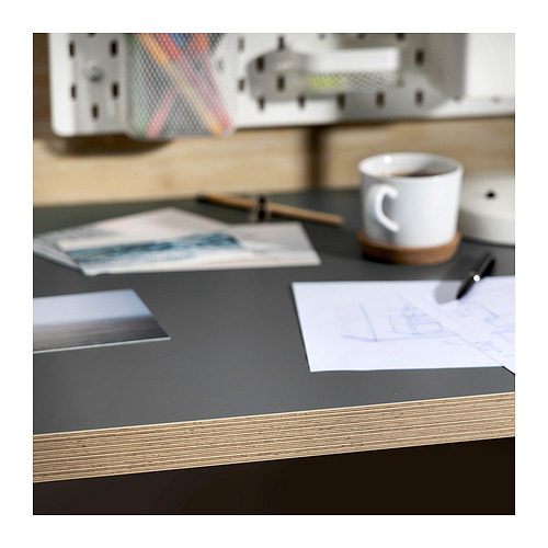 Escritorio con tapa gris LAGKAPTEN, papeles, bolígrafo y taza de café. Espacio de trabajo organizado con diseño moderno.