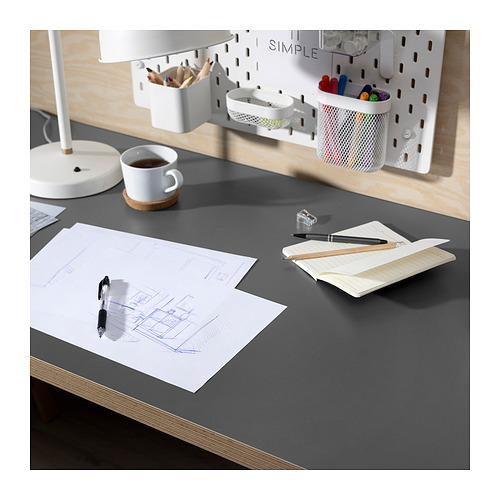 Configuración de escritorio limpia y moderna con lámpara blanca, taza de café, bloc de notas, bolígrafos y bocetos.
