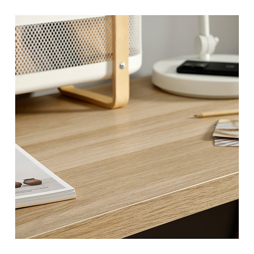 Montaje de escritorio minimalista con revista abierta, lápices y lámpara blanca sobre mesa de madera clara.