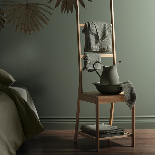 Un moderno soporte de madera en una sala verde con toallas y una regadera.
