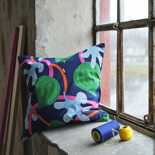 Cojín MÄVINN con diseño de frutas en el alféizar de la ventana, junto a la lana.