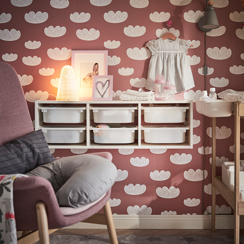 Acogedora guardería con paredes de nubes rojas, lámpara suave, sillón gris, almacenaje blanco.