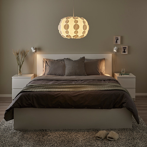 Dormitorio moderno y acogedor con cama gris, luz redonda y zapatillas.