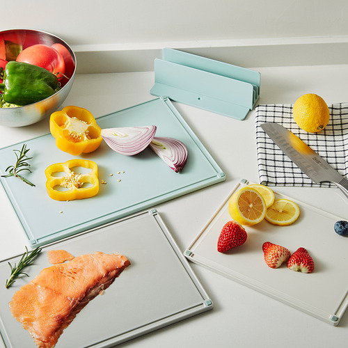 Tres tablas de cortar de color azul claro con diferentes ingredientes: pimiento morrón en rodajas, cebolla morada, limón, fresas, salmón y cuchillo, almacenadas ordenadamente.