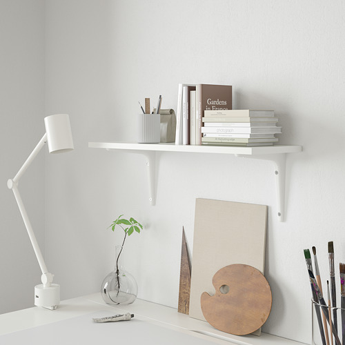 Estantería de pared blanca BURHULT con libros y materiales de arte.