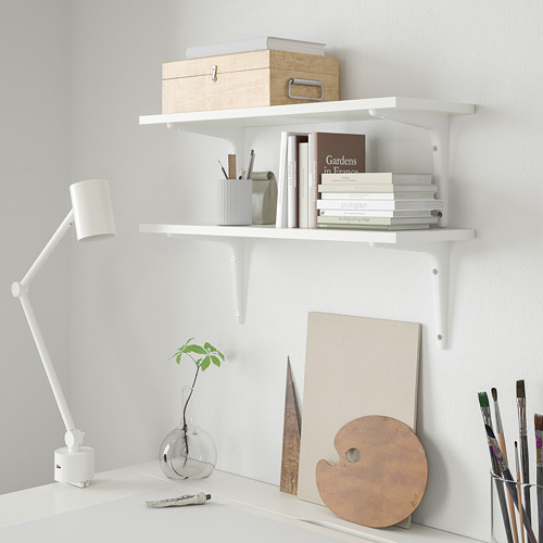 Dos estanterías BURHULT con libros y material de arte. Escritorio con planta y lámpara.