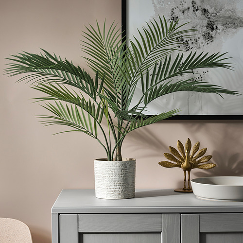Decoración moderna del baño con plantas verdes y arte dorado cerca del tocador.
