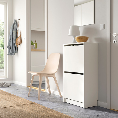 Pasillo moderno con zapatero blanco, silla y almacenamiento para colgar.