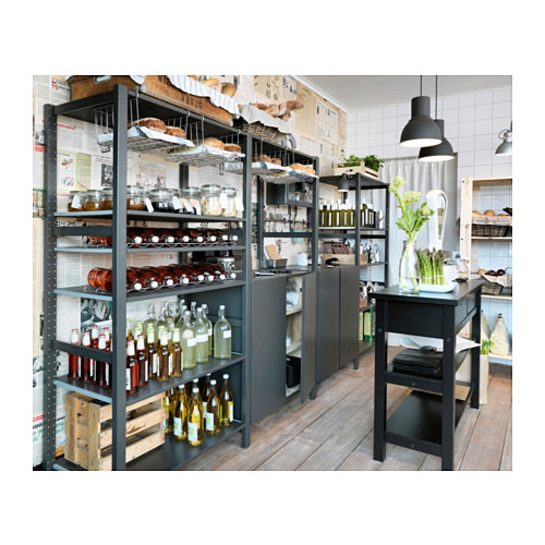 Cocina moderna con estantes y mesa IVAR negros, que exhiben frascos, botellas, cajas y plantas.