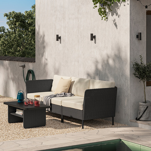 Patio moderno con sofá de mimbre VITTSKÄR , mesa de centro y plantas colgantes.