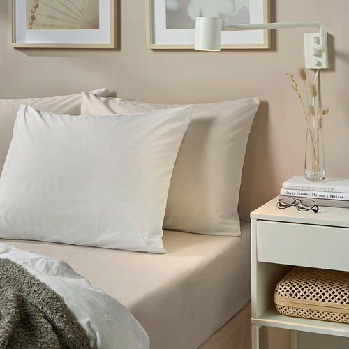 Almohadas de lujo beige de la DVALA en la cama, grandes y rectangulares de algodón suave, con mesita de noche minimalista, jarrón de flores, libros, gafas, decoración elegante de la habitación.