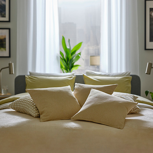 Descripción de la imagen: una cama acogedora con cojines SANDTRAV beige y texturizados, con detalles amarillos verdosos, que agregan calidez y comodidad a la habitación.