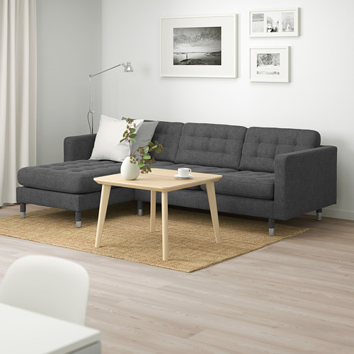 Sala de estar moderna con sofá landscrona gris oscuro, mesa de centro de madera clara y cuadros enmarcados en blanco y negro sobre una pared clara.