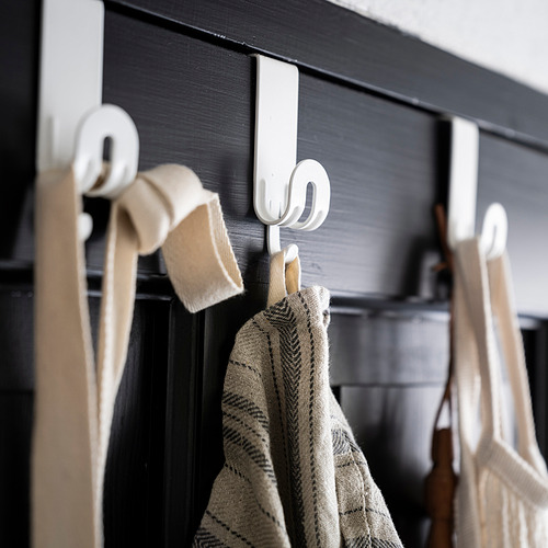 Ganchos de metal blanco cuelgan de una superficie de madera oscura, sosteniendo toallas de colores claros.