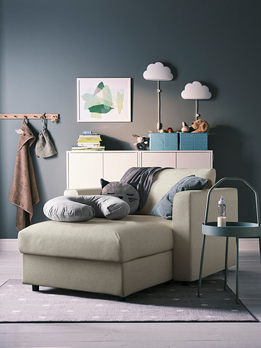 Acogedora sala de estar con sofá beige VIMLE, almohadas grises, mesa auxiliar y estantería colorida contra la pared verde.