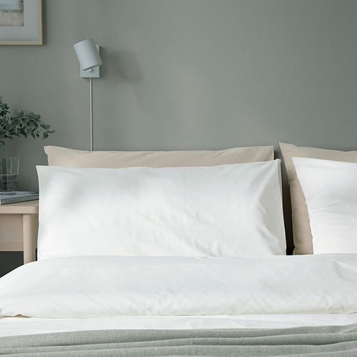Funda de almohada de algodón DVALA blanca en la cama con planta y cristal.