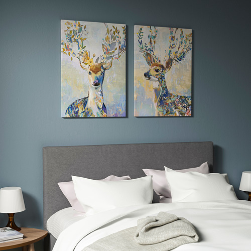 Dormitorio azul con estampados de ciervos en lienzo sobre ropa de cama blanca.
