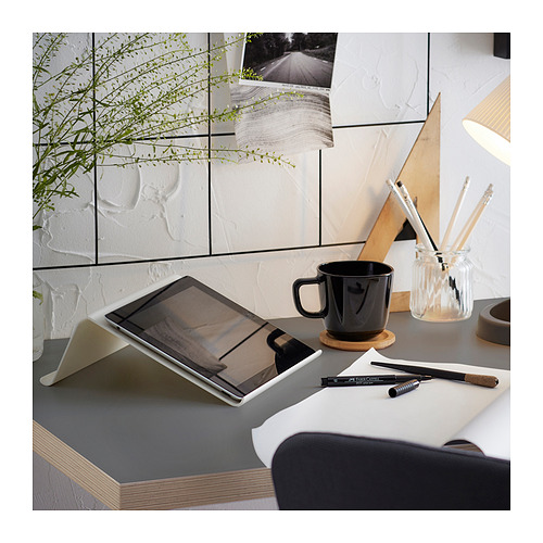 Configuración de oficina en casa con escritorio LAGKAPTEN con tableta, taza negra, bolígrafos y planta.