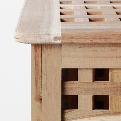 Primer plano del borde de las mesas de madera. Muestra madera de acacia lisa y robusta con patrón de vetas naturales. Acabado limpio y detalle preciso de la carpintería.