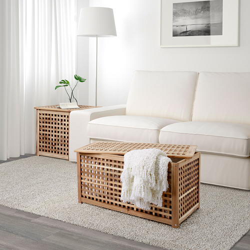 Acogedora escena de sala de estar: sofá crema, mesa auxiliar de celosía de madera con manta, alfombra y planta.
