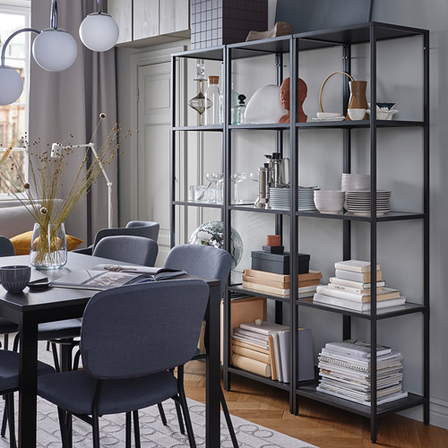 Plato moderno con sillas, estanterías negras, decoración, ventana.