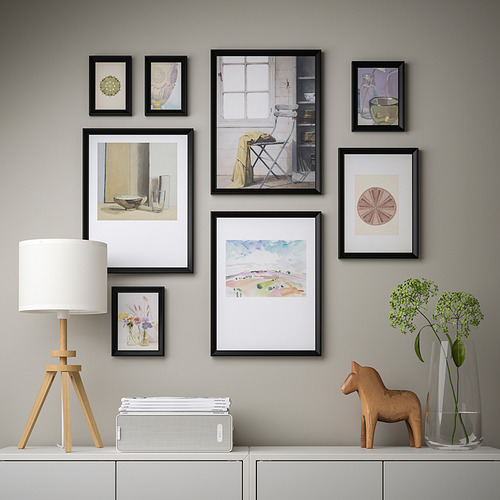 Pared de la galería con arte enmarcado, lámpara minimalista y caballo de madera en el aparador.