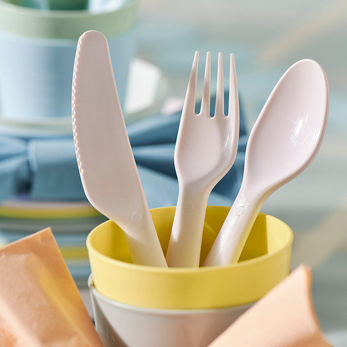 Juego de utensilios de plástico en soporte amarillo: cuchillo, tenedor, cuchara, disposición ordenada.