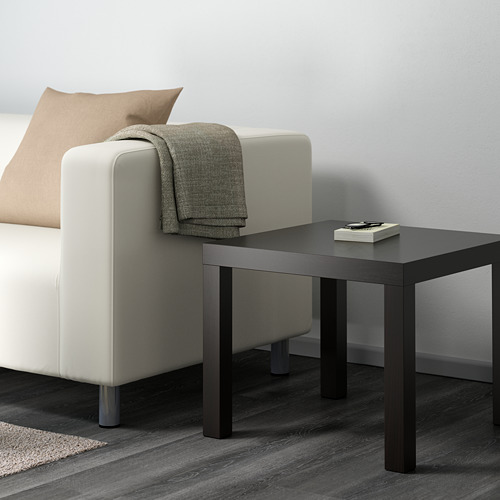 Mesa de centro NEGRA junto a sofá blanco, con libros y cojines.
