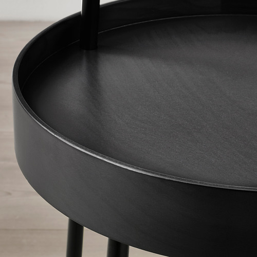 Mesa auxiliar circular negra con bordes lisos y altos y un asa en la parte superior para facilitar su transporte.