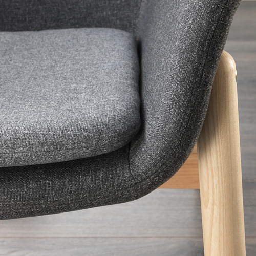 Primer plano de un moderno sillón acolchado con elegantes reposabrazos de madera y felpa gris oscuro. Destaca el diseño ergonómico de alta calidad.