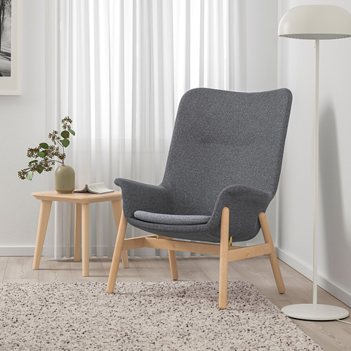 Moderno living comedor con sillón VEDBO gris, mesa auxiliar de madera y lámpara de pie.