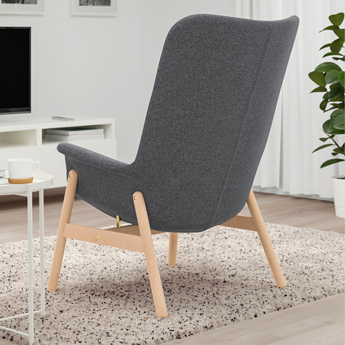 Sillón moderno con respaldo curvo gris oscuro para apoyo lumbar sobre patas de madera clara. Adecuado para relajarse y socializar en espacios abiertos.