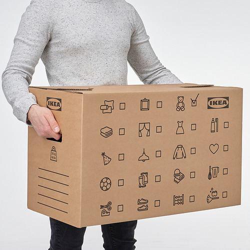 Persona sosteniendo una gran caja de cartón para mudanzas con la etiqueta ikea con asas recortadas y varios símbolos que indican el contenido.