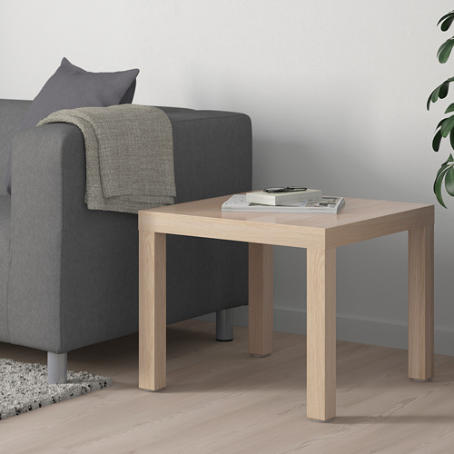 Mesa auxiliar LACK, de color marrón claro, junto a un sofá gris, contiene revistas.