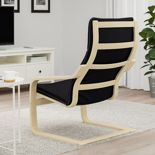 Silla de madera acolchada negra, reclinada, cerca de una pequeña mesa blanca con una taza y un posavasos.